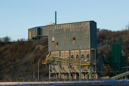 Quarry building made of corugated metal with a conveyor belt and steps on the outside.