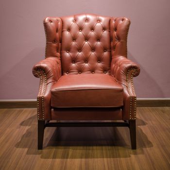 Front of Classic Chesterfield luxury Brown Leather armchair on Wood floor