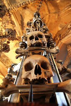 The Sedlec Ossuary is a small Roman Catholic chapel, located beneath the Cemetery Church of All Saints, in the Czech Republic. The ossuary is estimated to contain the skeletons of between 40,000 and 70,000 people, many of whom have had their bones artistically arranged to form decorations and furnishings for the chapel. The ossuary is among the most visited tourist attractions of the Czech Republic, attracting over 200 thousand visitors yearly.