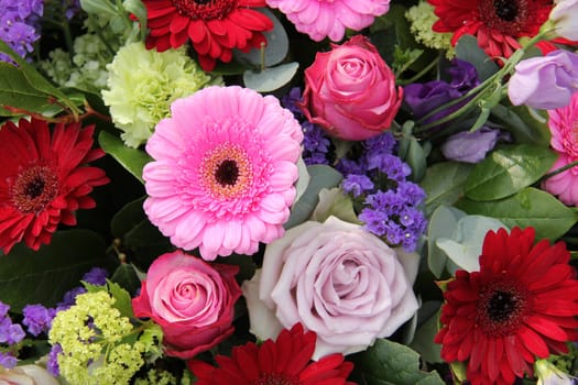 Red and pink gerberas, together with purple roses and other flowers in a wedding arrangement