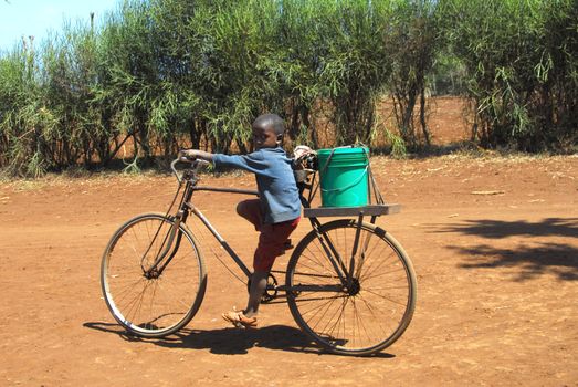 Mtito Andes,Kenya 13 JULY 2009:child carries the water with your bike thanks to various humanitarian organizations,the people of the village of Andes Mtito can fetch water from a source.Mtito Andes is a village close Kilimanjaro and the lack of water is very serious