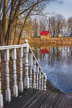 railing with balusters on the background of a wooden cottage with a red roof in the countryside