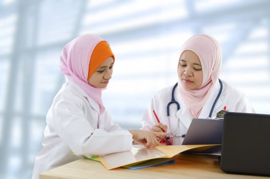 Two Muslim female doctor discussing patient report