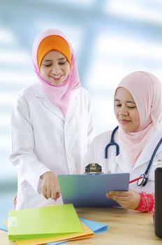 Two female Muslim doctor discussing on medical report