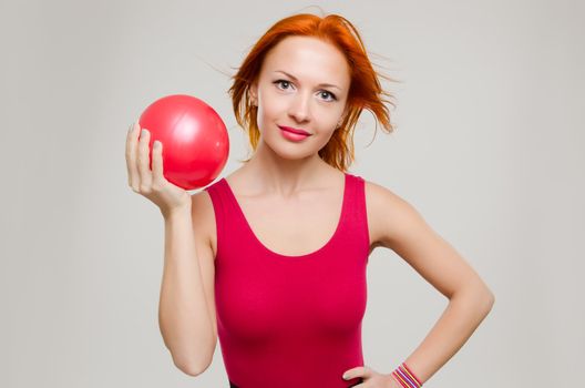 Beautiful fitness model posing with fit ball wearing red swimsuit