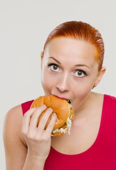 Beautiful young red woman eating juicy burger