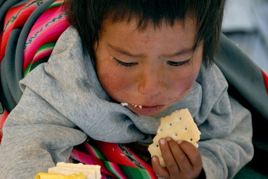 La Paz, Bolivia in September 2009: A child on the shoulders of the mother eats a biscuit