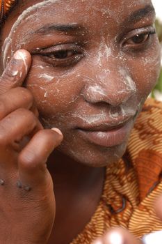 Mozambique Island, Mozambique, may 2, 2004: African woman with the cream of Musiro a paste obtained by rubbing a stone on a piece of a tree branch Olax locale.Il miraculous mixture is used to treat the skin. Does it make it softer and removes stains.