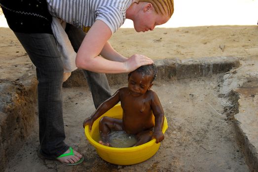 Mwanza,Tanzania, February 8, 2010: Albino girl who washes a baby in the basin.Tanzania is the African region with more albinos. By the year 2006 albino people are killed for witchcraft rituals