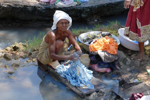 Nosy Be, Madagascar- 16 October, 2006: An old woman washing clothes in a river. Many areas Nosy Be suffer from intense and prolonged drought.