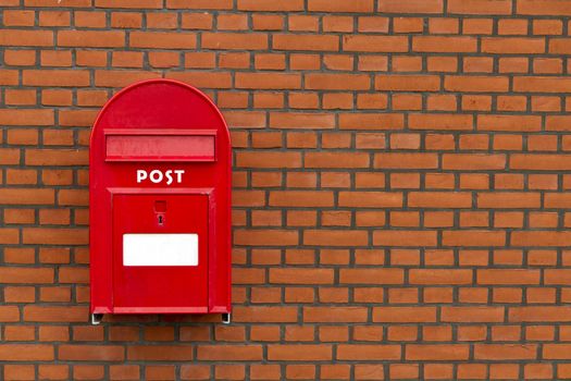 red mailbox on stone wall wit copy-space on bricks