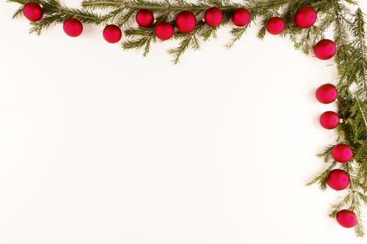 Border of red christmas garland with baubles and ribbons on white.