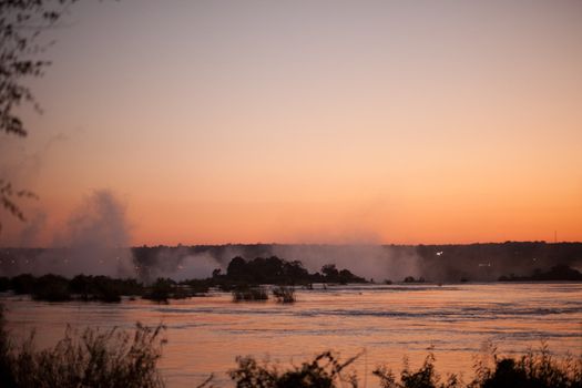 Plume of mist rising from Victoria Falls at sunset