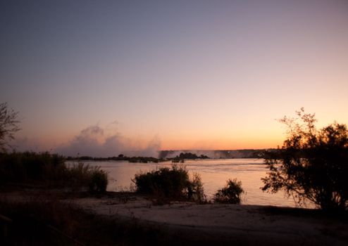 Plume of mist rising from Victoria Falls at sunset