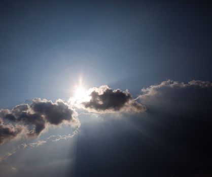 Sun peeking out from behind clouds and blue sky