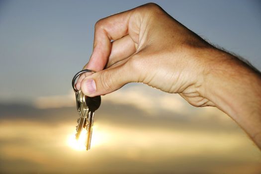 Hand holding keys against sunset, sun is shining throug the keys!!