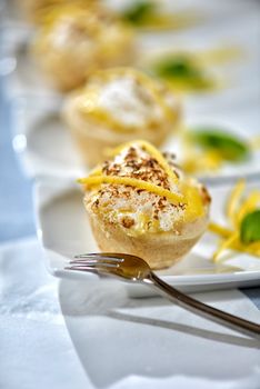 Image of lemon meringue tarts with garnish on white plates