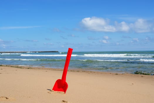 a red shovel at the beach on a sunny day