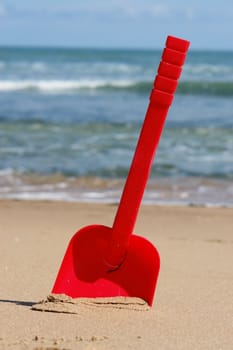 a red shovel at the beach on a sunny day