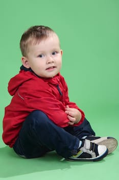 The boy in a red jacket on a green background