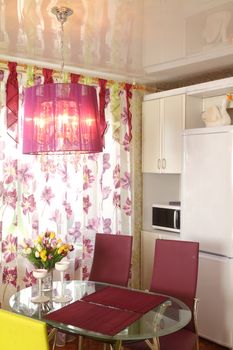 Modern kitchen. A bunch of flowers on a glass little table opposite to a window