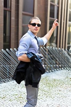 Portrait of successful young guy with jacket in hand against urban background