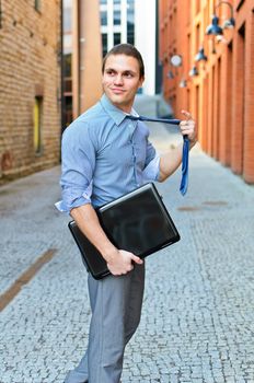 Young guy posing with a laptop on the street.