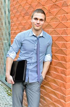 Portrait of a student with a laptop standing at the wall
