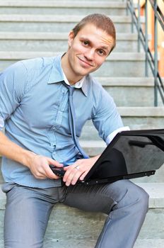 Young guy with a laptop sitting on the stairs