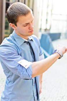 Successful man looking at his watch. Over urban background.