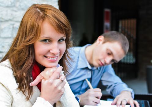 Business partners meeting: Male and female sitting outdoors. Focus on female.