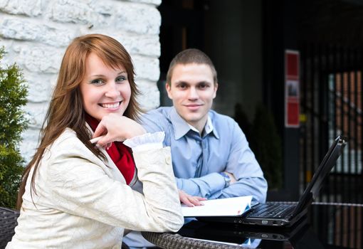 Business partners meeting: Male and female sitting outdoors. Focus on female.