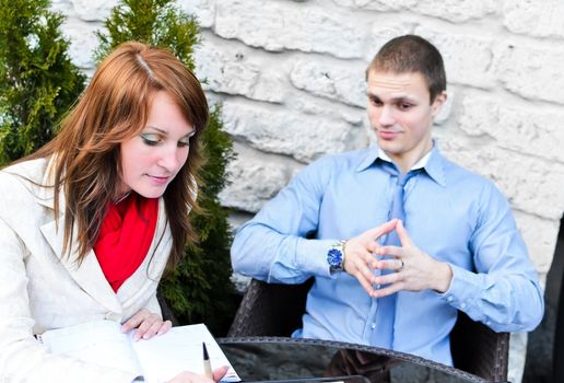 Business partners meeting: Male and female sitting outdoors. Focus on female.