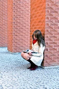 Female sits and reads a book at the wall