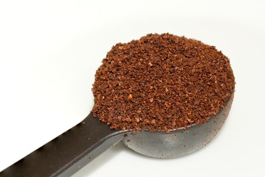 One scoop of fresh ground coffee forming a heap in a plastic spoon