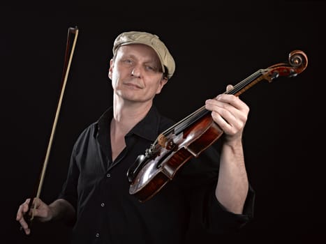 Portrait of a man holding a  wooden violin on black background