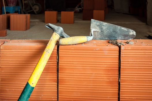 Hammer and trowel on brick wall in construction masonry site