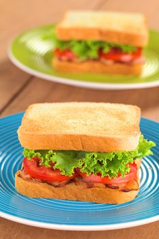 Fresh homemade BLT (bacon lettuce and tomato) sandwich on colorful plates (Selective Focus, Focus on the front of the first sandwich) 