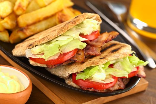 Fresh homemade BLT (bacon lettuce and tomato) wholewheat pita sandwich with French fries on metallic plate with mayonnaise and juice (Selective Focus, Focus on the front of the two pita stuffings) 