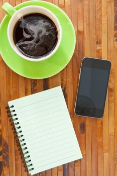 green cup of hot coffee smartphone and book on wood background