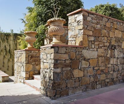 Generic garden featuring stone carved plant pots and random local stone masoned wall