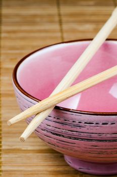 Empty pink rice bowl on bamboo mat