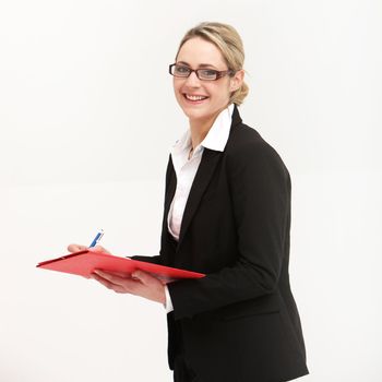 Smiling friendly secretary or assistant wearing glasses writing in a file which she is holding in her hand