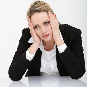 Dejected depressed businesswoman sitting with her face in her hands and her elbows resting on a table top