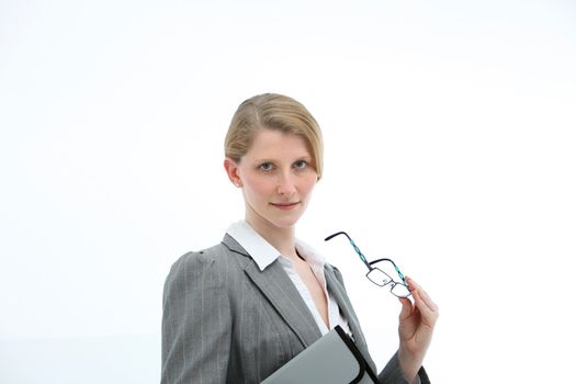 Serious businesswoman with her glasses in her hand and carrying a folio watching the camera and listening
