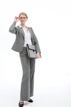 Stylish businesswoman in an elegant grey suit standing adjusting her glasses and holding a folio, full length isolated studio portrait
