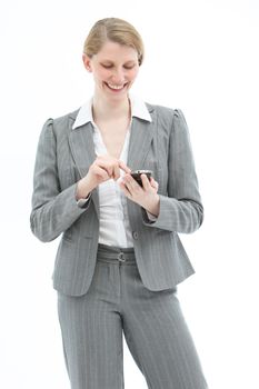 Happy professional woman in a stylish slacksuit standing texting on her mobile phone isolated on white