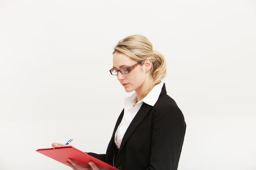 Conscientious secretary concentrating on the notes she is writing in a handheld file isolated on white
