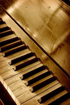 Photo of an old dirty well-worn piano keyboard done in sepia.
