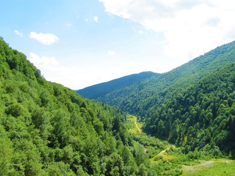 Panoramic view of a valley between green mountains in a sunny day     